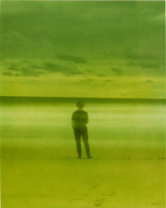A ghostlike self-portrait standing on the beach and looking towards the sea.