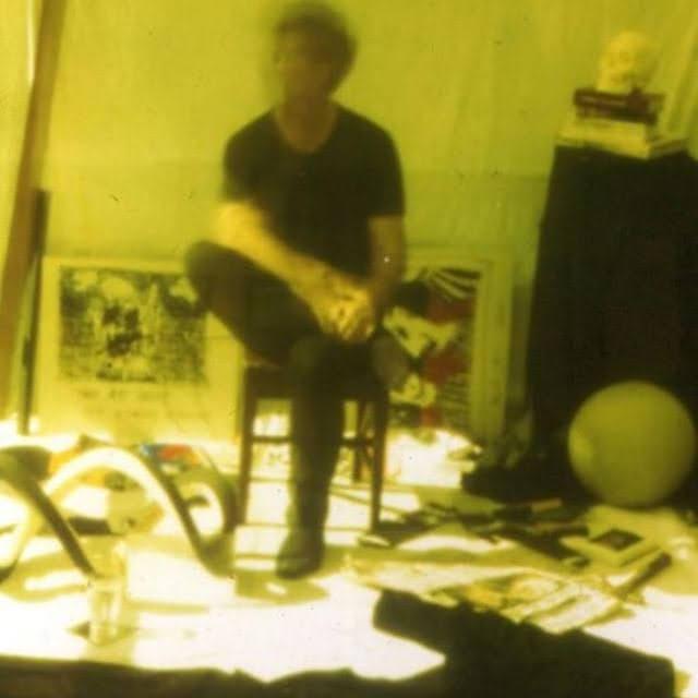 A yellow-toned self-portrait in the Woy Woy Bay studio, with photographs and materials on a table.
